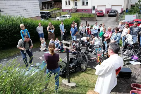 Diakon Steffen Dully segnet in Riedelberg beim Gottesdienst vor der Kirche Fahrräder, Roller, Kinderfahrzeuge und fünf Traktoren