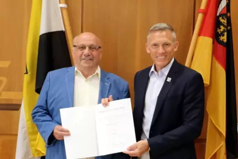 Landrat Ralf Leßmeister (rechts) überreicht Hermann Jung aus Hütschenhausen die Landesehrennadel für langjähriges Engagement. 