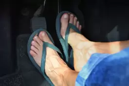 Frau mit Flip Flops am Steuer eines Autos