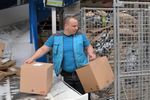 Dieser Mann aus der Ukraine packt Päckchen und Pakete an einer Sortieranlage im Logistikzentrum des Paketdienstleisters Hermes i