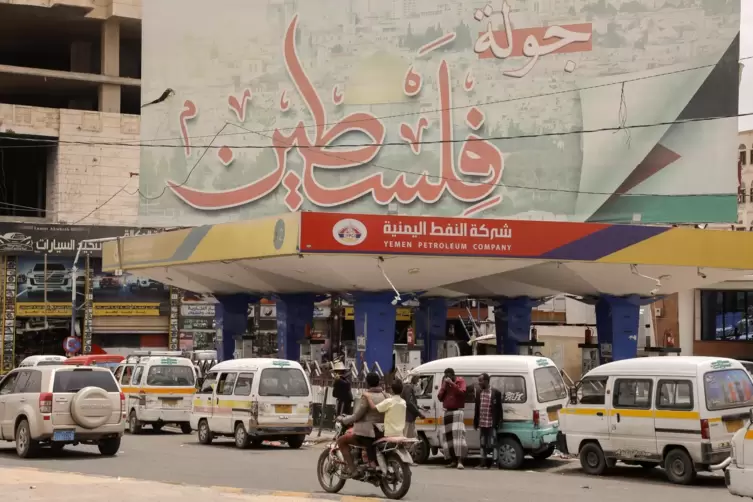 Jemen, Sanaa: Jemeniten fahren an einem riesigen Plakat mit dem Slogan: „Jetzt ist Palästina dran“ zur Unterstützung der Palästi