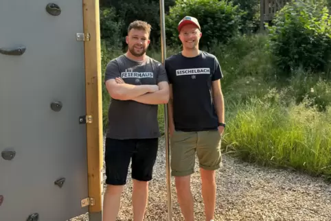 Lars Jacob (links) und Tim Altschuck stehen neben dem neusten Bauprojekt des KKJ: der Kletterwand auf dem Spielplatz. 