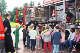 Daniel und Oliver erklären den Kindern, wie ein Feuerwehrauto beladen wird.