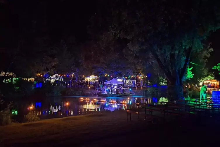 Bunte Illumination beim Sommerfest, die sich im Landschaftsweiher in Katzweiler spiegelt.