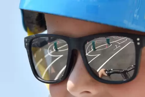 Ein Junge trägt eine Sonnenbrille auf einem Fahrrad-Parcours