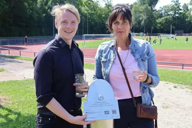 Bürgermeister Lukas Hartmann und Mitarbeiterin Andrea Böhm testen den neuen Trinkwasserbrunnen im Südpfalzstadion. 