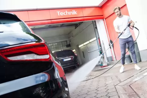 Ein Mann wäscht an einer Tankstelle sein Auto
