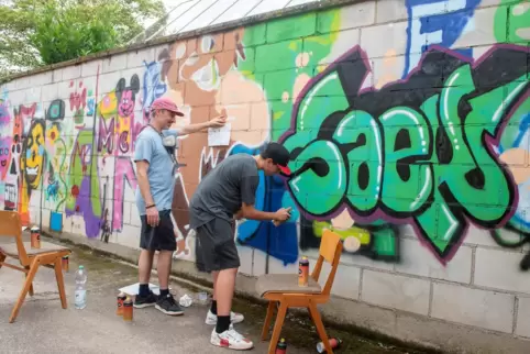 Schnell zaubern die jungen Talente ein großes Kunstwerk an die Mauer – links der Künstler Till Heim.