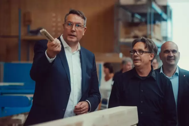 Ministerpräsident Alexander Schweitzer (links) lässt sich von Jürgen Gottschall den Holzbau erklären. Rechts Bürgermeister Manfr