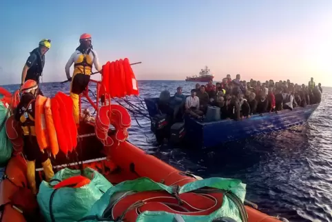 Die Seenotretter verteilen Rettungswesten an die Migranten, die in einem manövrierunfähigen Holzboot unterwegs sind. 