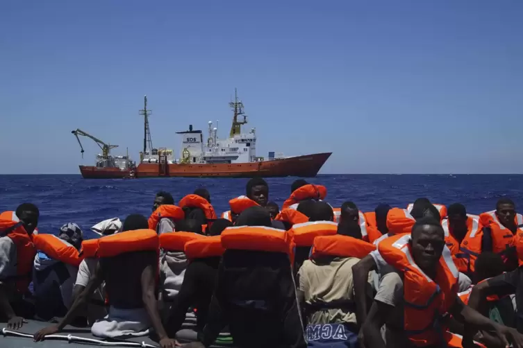 Flüchtlinge in einem überfüllten Boot auf dem Mittelmeer warten auf Rettung. 