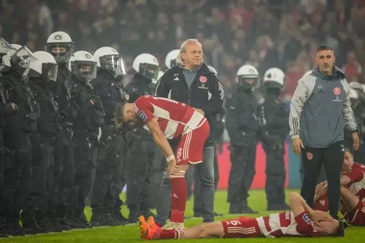 Am Boden zerstörte Spieler, Polizei auf dem Rasen als Schutzschild: ein Bild, das viel über die Relegation aussagt.