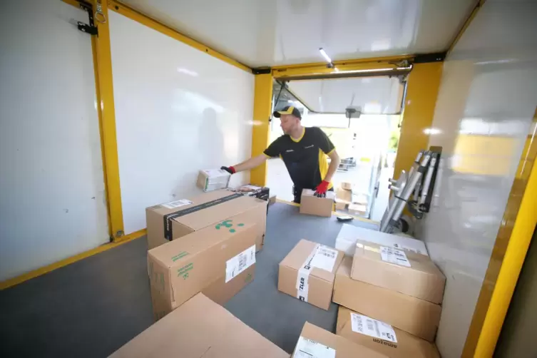 Felix Niebergall packt am Zustellstützpunkt der Post in Rehweiler Pakete und Päckchen ins Postauto.