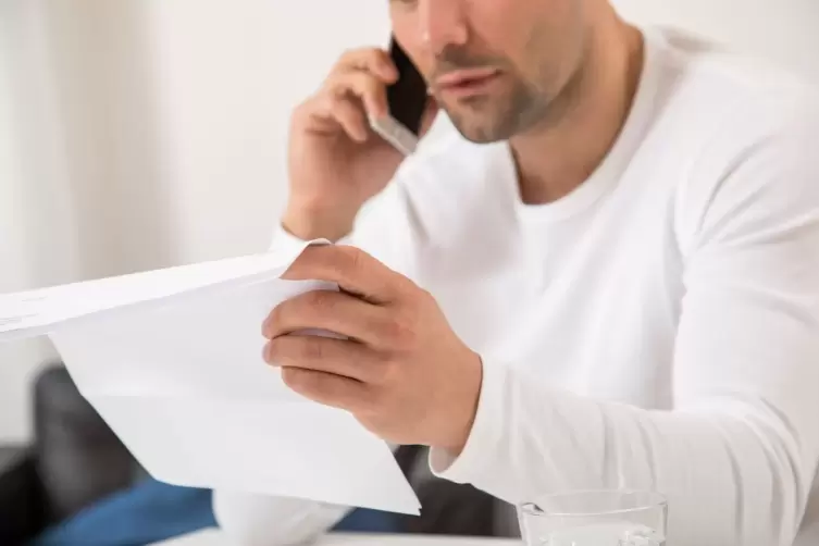 Ein Mann telefoniert und hält ein Schreiben in der Hand