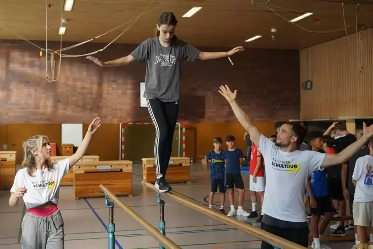 Achtklässlerin Nele balanciert geschickt im Parkour-Workshop über den Barren. Die Trainer Marleen Sichtermann und Kai Ortmann si