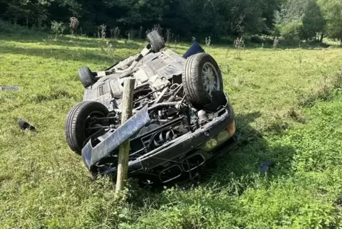 Der Unfallwagen ist auf einer Wiese auf dem Dach liegengeblieben. 