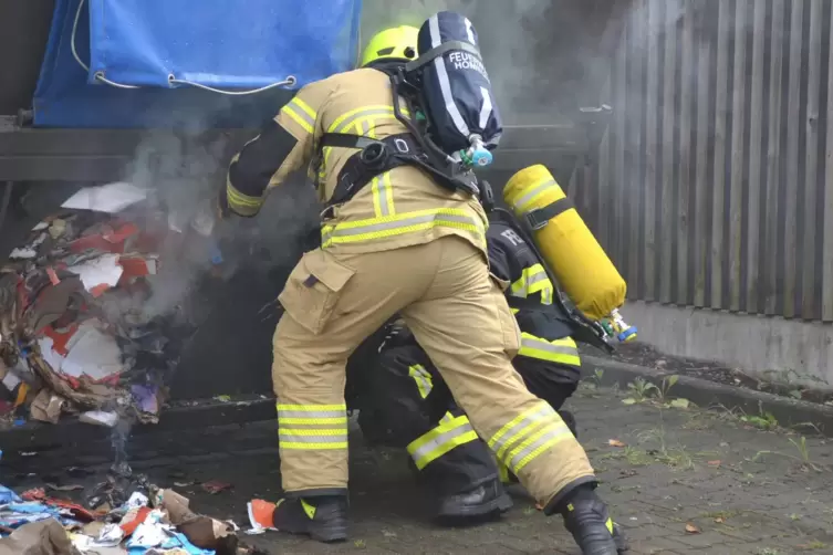 Unter Atemschutz löschen Feuerwehrleute den Brand im Papiercontainer des Aldi-Marktes in Homburg. 