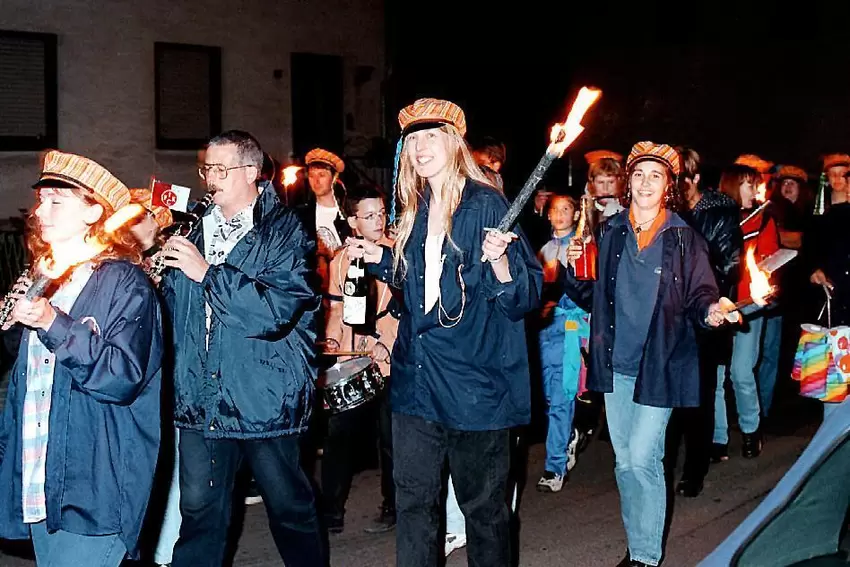 Umzug 2000: Die Kapelle braucht Licht, die Straußmädchen liefern es per Fackel. Sandra Abel, damals Wirth (Mitte), macht dieses