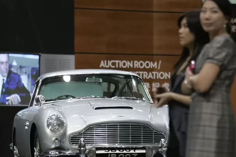 Zwei Chinesinnen stehen in Hongkong vor dem Aston Martin, den James Bond im Film „Goldfinger“ benutzte.