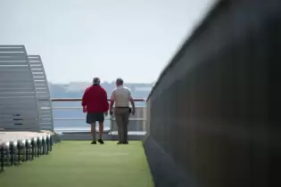 Ältere Passagiere auf dem Oberdeck eines Kreuzfahrtschiffs