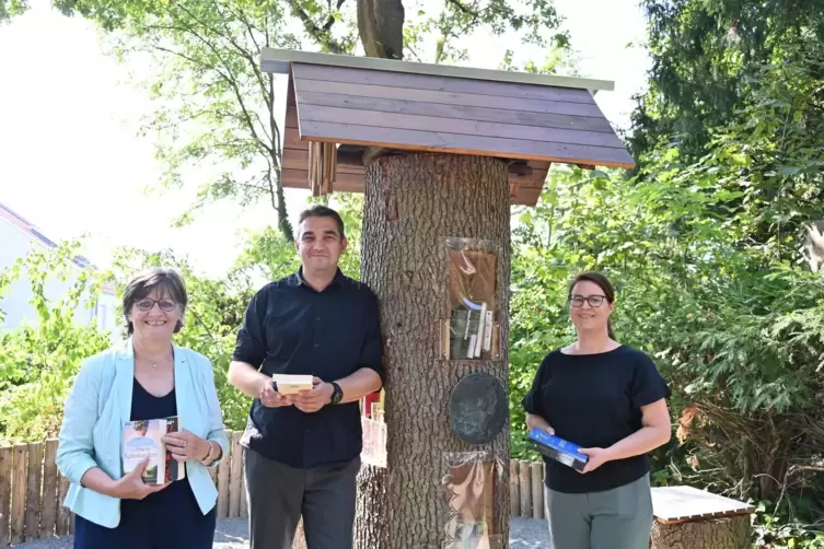 Bestücken den Bücherbaum auf dem Wormser Hauptfriedhof: Cordula Schönung (links), Christina Jung und Beigeordneter Timo Horst.