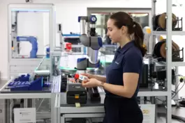 Larissa Theis von der SmartFactory KL zeigt an einem Demonstrator, wie sich das Modell eines Lkws in einer smarten Fabrik herste