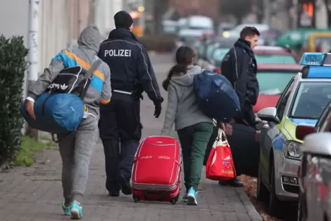 Abgelehnte Asylbewerber werden zum Transport zum Flughafen von Beamten abgeholt. 