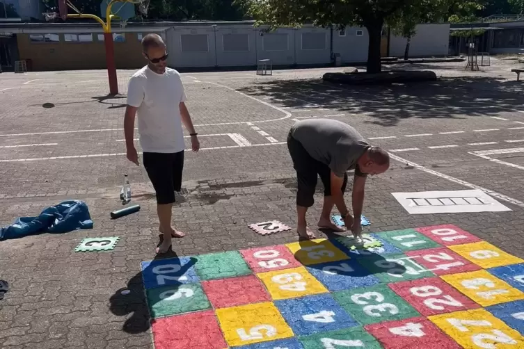 Beim Aufbringen eines Spielfelds auf dem Schulhof: Eltern von Dudenhofener Grundschülern. 