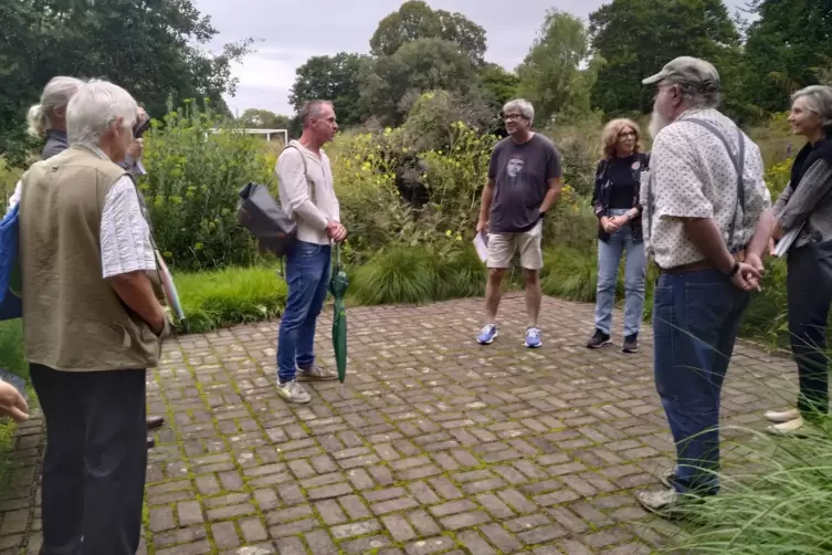 Harald Sauer (Mitte) erklärt den Denkmalgedanken im Quellgarten des Ebertparks.