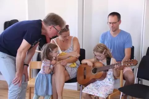 Gitarrenlehrer Volker Riegler (links) zeigt der sechsjährigen Martha, wie sie Töne auf der Gitarre erzeugen kann. 