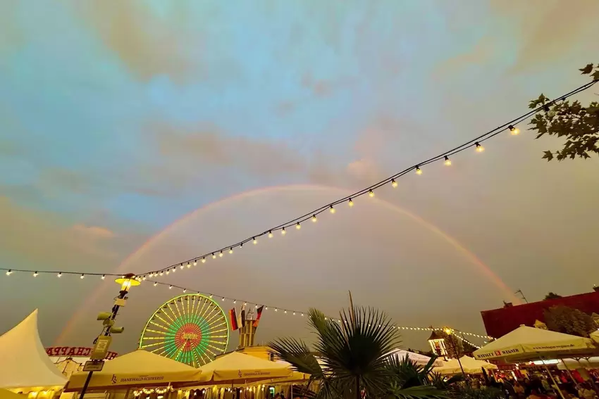 Da kann sogar das Riesenrad nicht mithalten: Ein Regenbogen macht den bunten Fahrgeschäften Konkurrenz. Geschossen hat das Foto