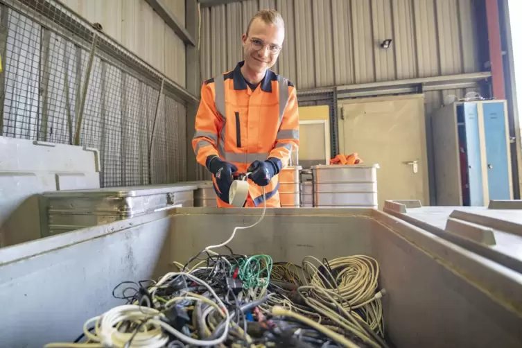 Praktikant Paul vor einem Container voller alter Kabel: Nach dem Aussortieren werden die Plastikmäntel entfernt, dann gibt es fü