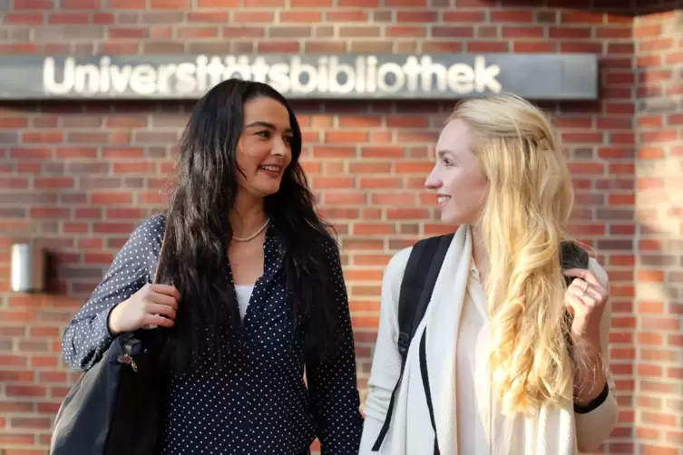 Zwei Frauen laufen eber den Campus der Universitaet