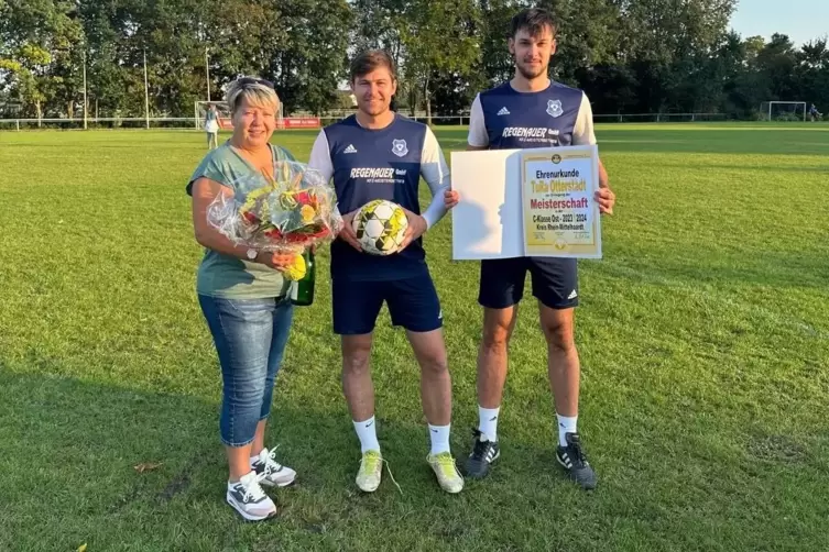 Blumen für die Kreisvorsitzende: Dana Burkard mit TuRa Otterstadts Trainer Markus Hajok (Mitte) und Kapitän Jannik Vogt.