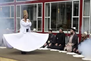 Ganz in Weiß und mit dem einen Grabstein symbolisierenden braunen Fez auf dem Kopf betritt der Derwischtänzer die Bühne.