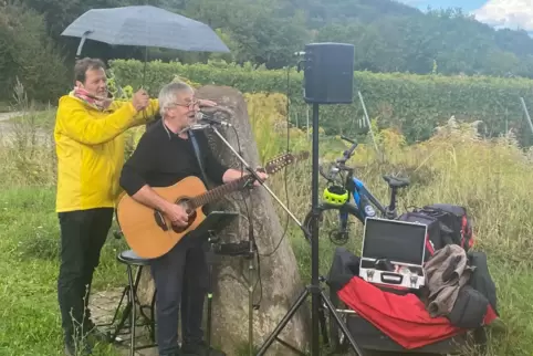 Wanderführer Rolf Schlicher beschirmt Sänger Ede Eber-Huber. Geregnet hat’s aber nur kurz.