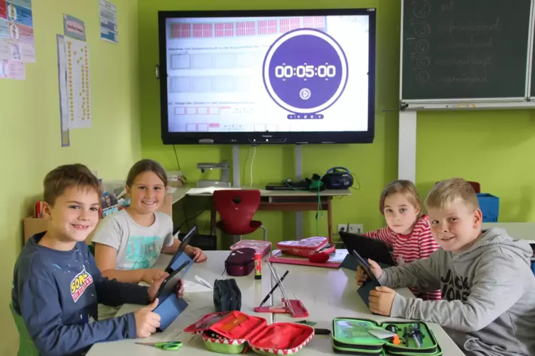 Rik, Mara, Emilia und Nick (vorne links nach vorne rechts) mit den neuen I-Pads vor dem Smartboard.