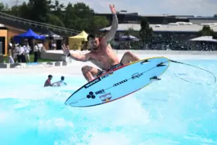 Leon Glatzer springt auf seinem Surfbrett über eine Welle bei der Eröffnung des o2 Surftown Muc, Deutschlands erstem Surfpark.