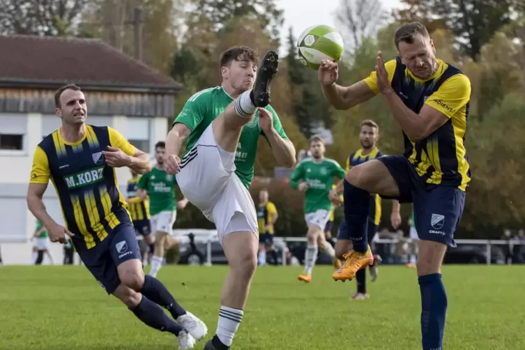  Leander Gerhard von der TSG Trippstadt (links) hebt den Fuß Richtung Ball und Fabian Schmitt von der SG Rockenhausen/Dörnbach.