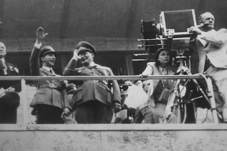 Leni Riefenstahl (bei der Kamera) während des Drehs von „Olympia“ mit Joseph Goebbels und Hermann Göring auf der Tribüne (1936).