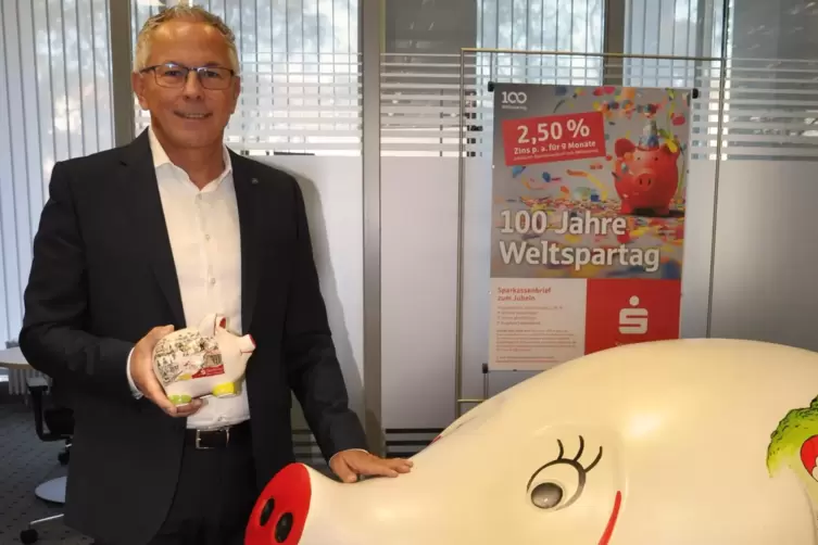 Hat als Kind sein Sparschwein zur Neustadter Sparkasse getragen: Sparkassen-Chef Andreas Ott mit Maskottchen und Jubiläumsschwei