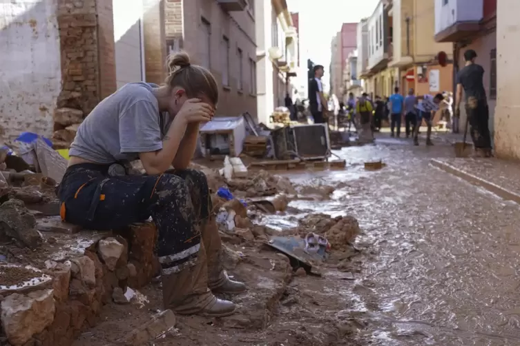 Eine Frau ruht sich kurz aus, während Anwohner und Freiwillige in Paiporta, in der Nähe von Valencia, aufräumen. 