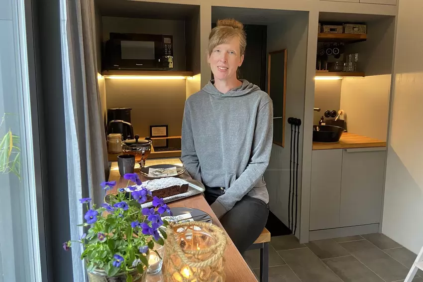 Sabine Kallenborn am gedeckten Kaffeetisch im Tiny House. Vieles, was es in dem kleinen Ferienhäuschen gibt, erfüllt gleich zwei