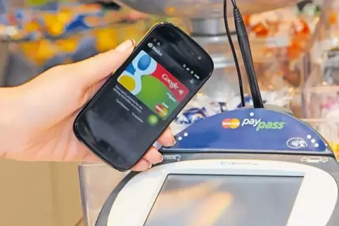 Ein Google-Smartphone wird an einer Supermarkt-Kasse neben ein PayPass-Gerät zur elektronischen Zahlungsabwicklung gehalten und 