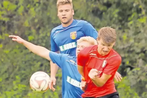 Umkämpfter Ball, umkämpftes Duell zweier Bezirksliga-Aufsteiger: Felix Moehler (Mitte, blaues Trikot) vom FV Rockenhausen gegen 