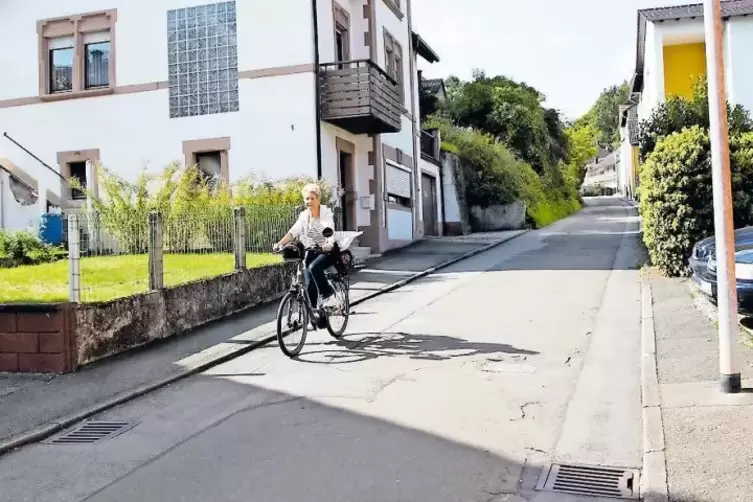 Die Radfahrerin kann es rollen lassen, denn die Heinrich-Heine-Straße in Oberauerbach ist eine Straße mit Gefälle.