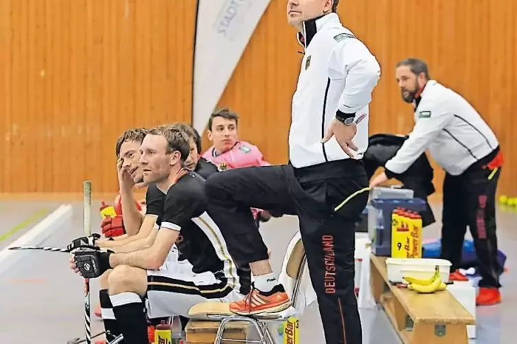 Bundestrainer Stefan Kermas (Mitte), Physiotherapeut Mark Bicker (rechts) und die Auswechselspieler beobachten ihr Team.