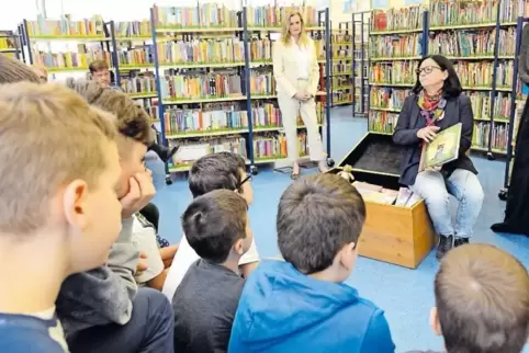 Elvira Gensheimer erklärt den Schülern aus der Gräfenauschule, welche Bücher in der Kiste sind. Nils Nager sitzt ebenfalls in de