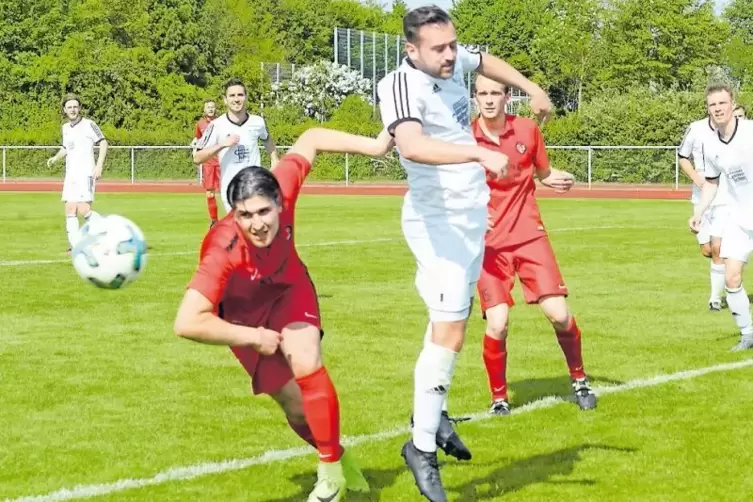 Jockgrims Burak Kilinc (rotes Trikot) und Philipp Jardot von der FG 08 Mutterstadt verfehlen den Ball.