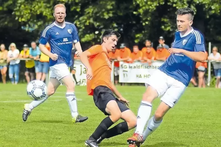 Der Waldfischbacher Dennis Scherrer (Mitte) wird von Bolandens Spielertrainer Joachim Lawall (rechts) gestellt. Links beobachtet